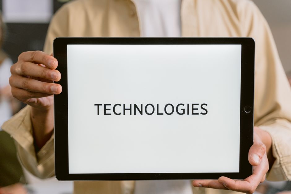 Close-up of a person holding a tablet with the word Technologies on the screen